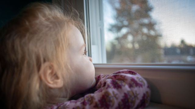 Un enfant pensif regarde par la fenêtre.