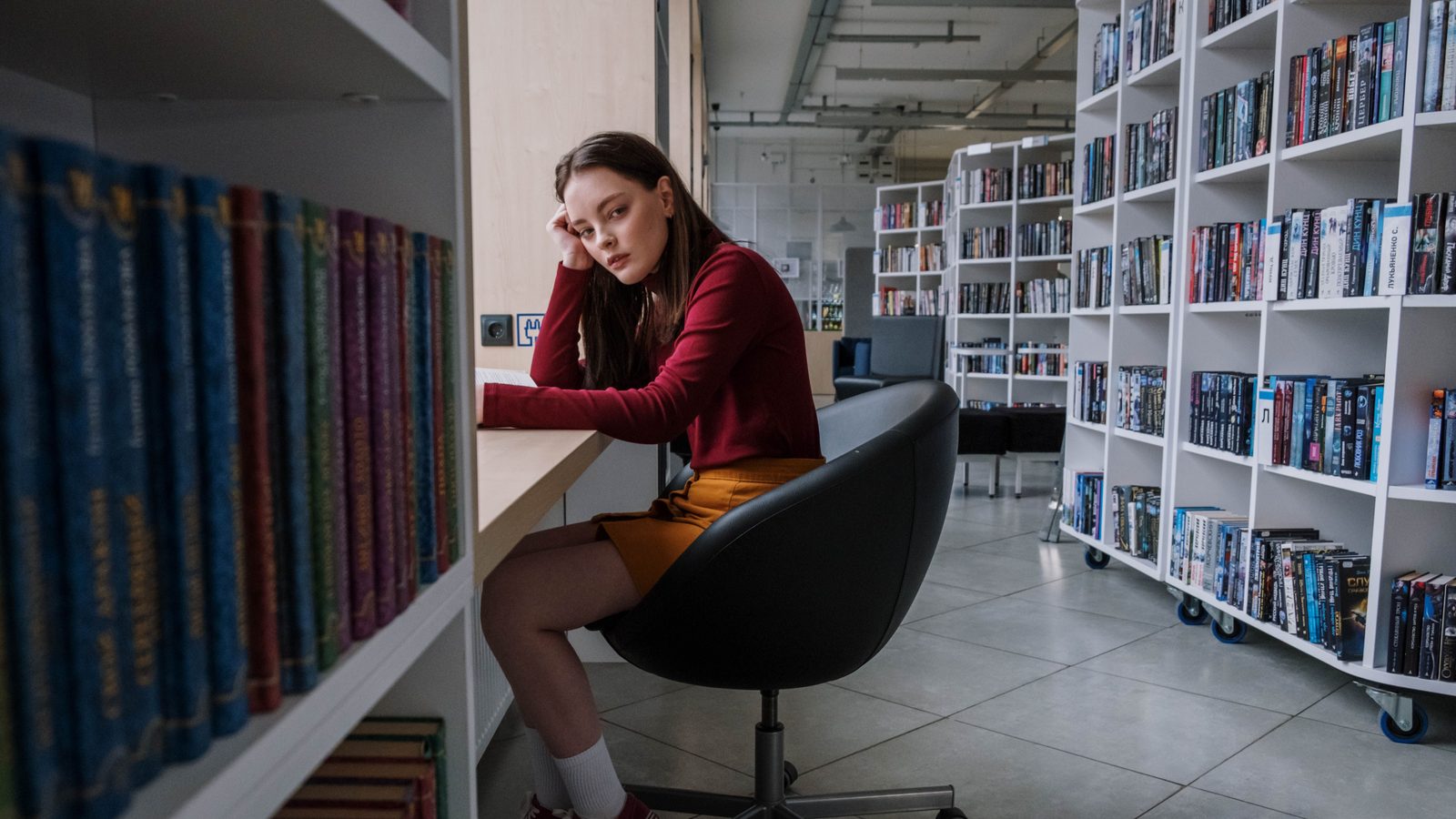 Une adolescente lit dans une bibliothèque moderne.