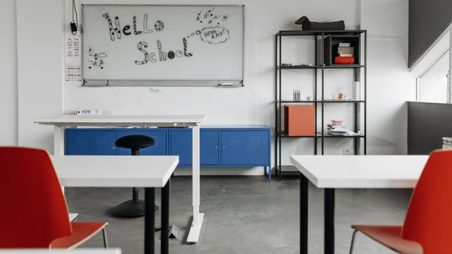 Une salle de classe moderne et vide, avec bureaux et tableau blanc.