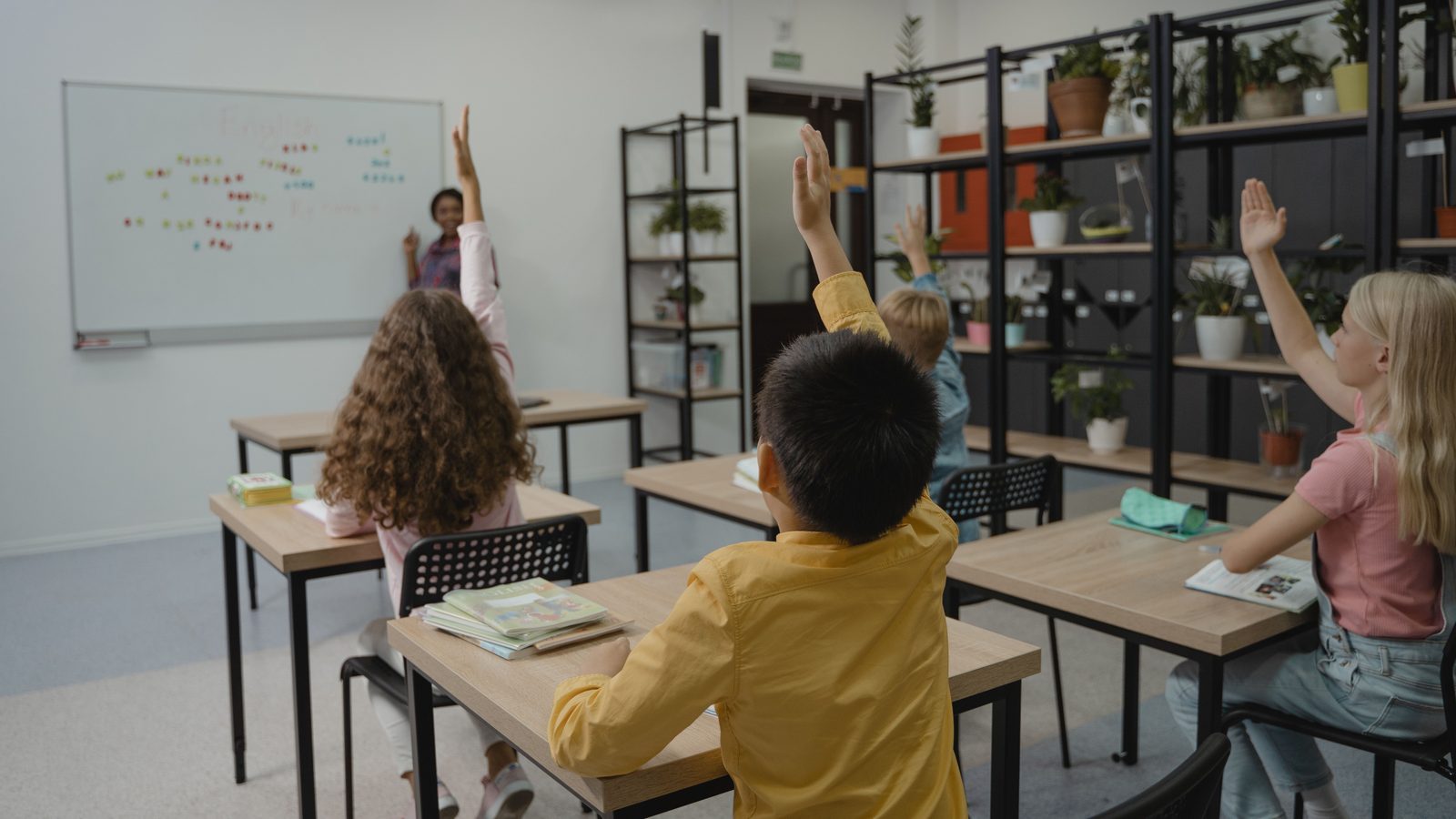 Des élèves lèvent la main dans une salle de classe animée.