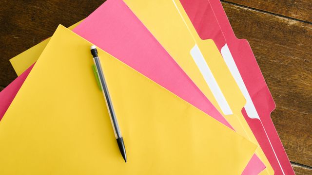 Des dossiers et classeurs colorés posés sur une table.