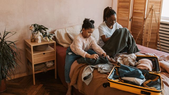 Une mère et sa fille plient des vêtements en préparant une valise.