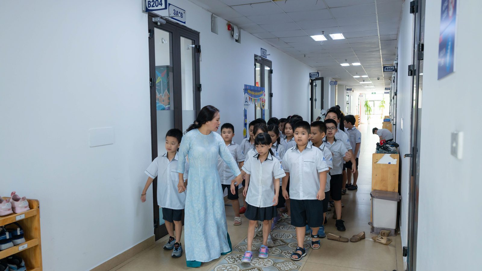 Un adulte guide un groupe d'élèves dans le couloir d'une école.