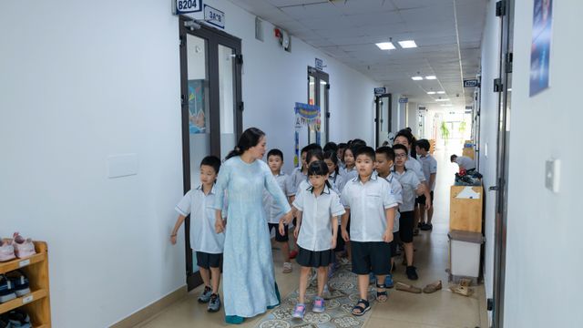 Un adulte guide un groupe d'élèves dans le couloir d'une école.